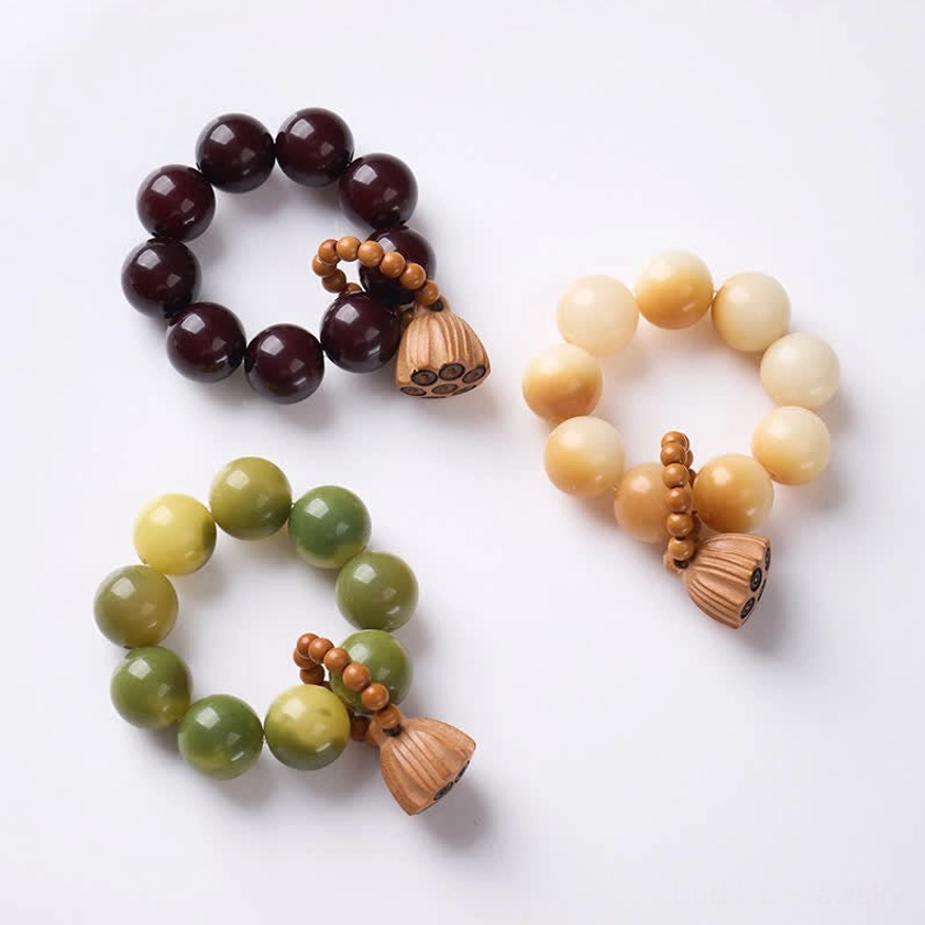 Three bodhi seed meditation bracelets with polished round beads and carved lotus charms on white background