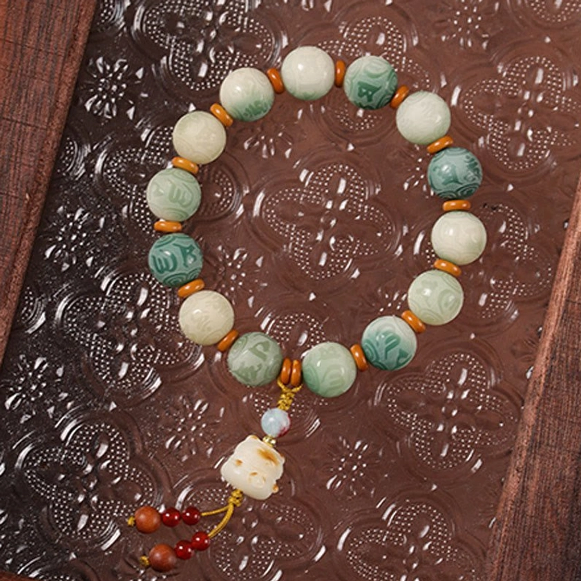 Handcrafted Bodhi seed bracelet with carved patterned beads and protective charm on embossed wooden board