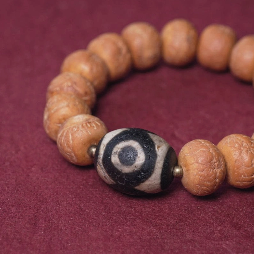 Close-up detail of barrel-shaped bodhi beads and three-eye dzi bead with metal spacers