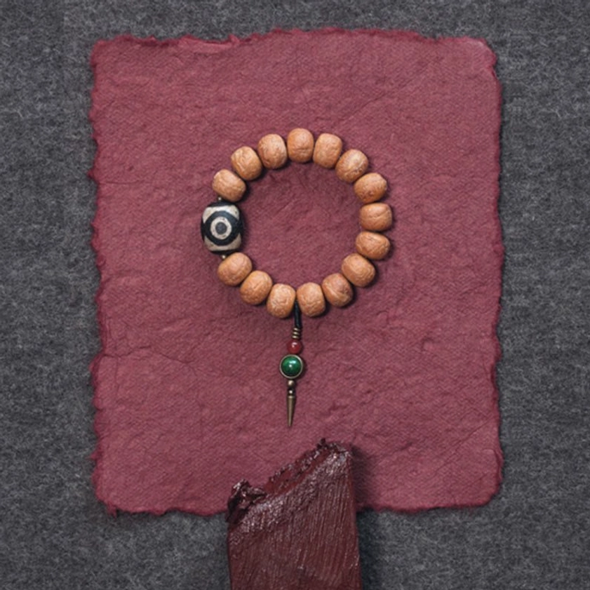 Bodhi seed and dzi bead mala bracelet displayed on dark and gray fabric background