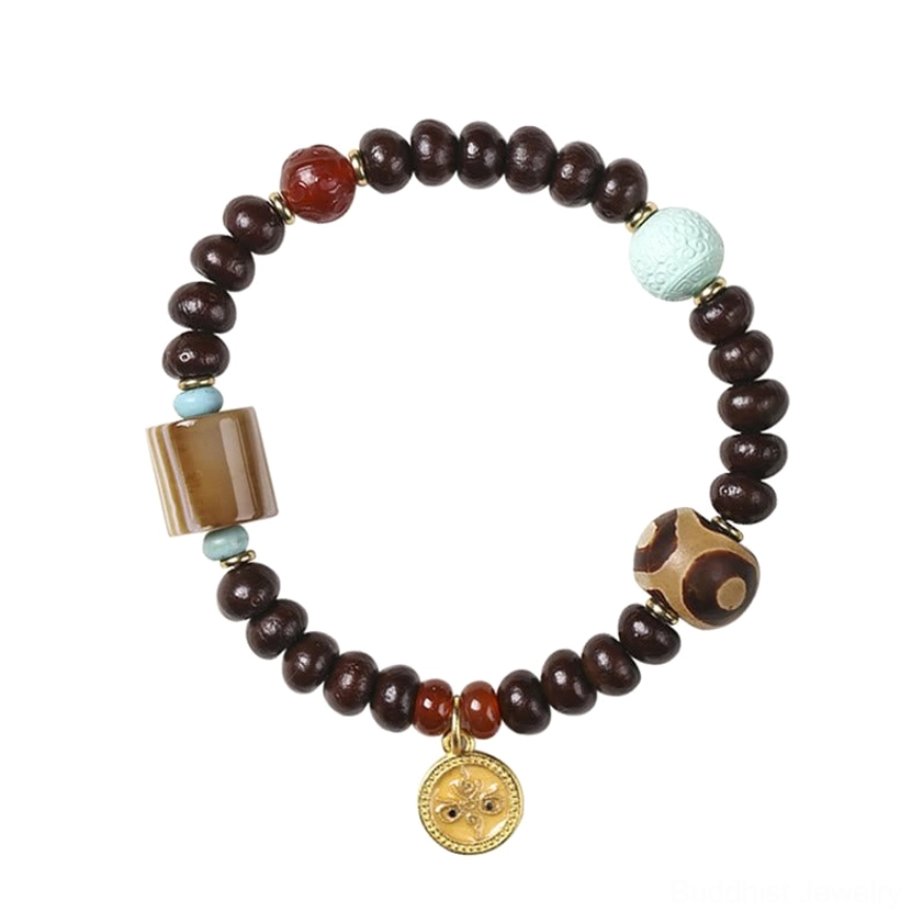 Authentic Buddhist bracelet with purple bodhi seeds, three-eye dzi bead, and round gold charm on table