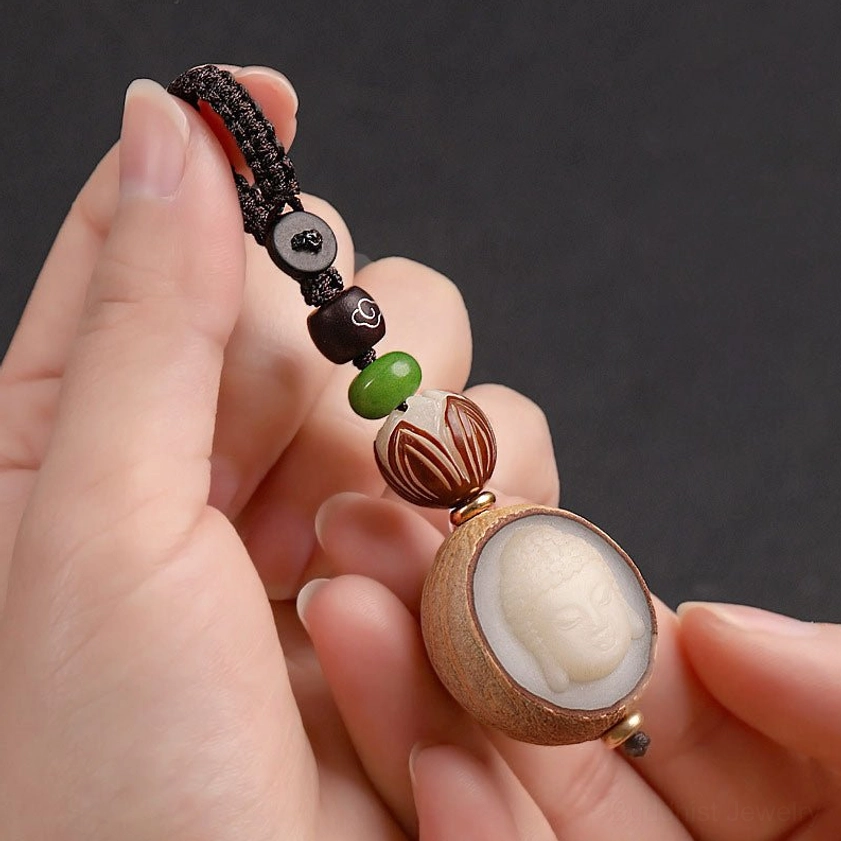 Close-up hand-held view of carved Buddha face on natural bodhi seed keychain pendant