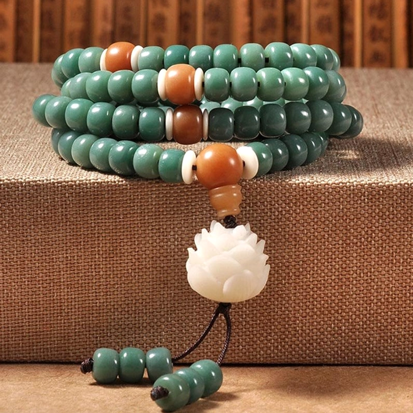 Bodhi seed lotus bracelet overhead view with teal barrel beads, brown spacers, and white lotus pendant on natural linen