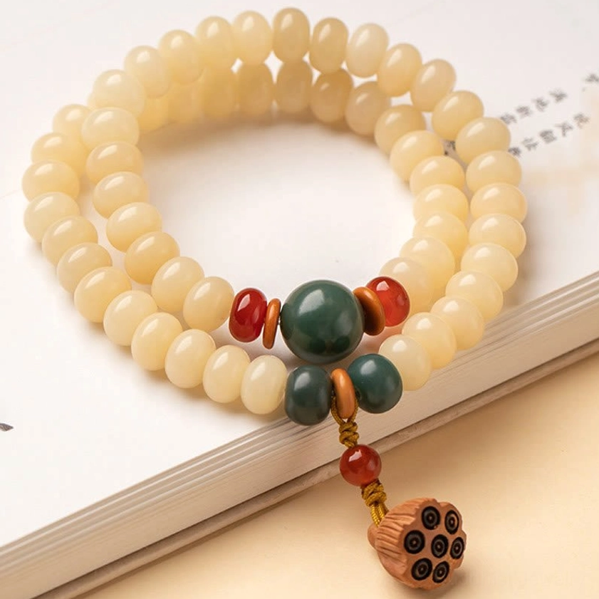 Bodhi seed double wrap bracelet flat lay on book surface with green and red accent beads