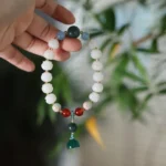 Bodhi seed lotus carved bracelet with white lotus beads and gemstone charms on natural bamboo leaf background