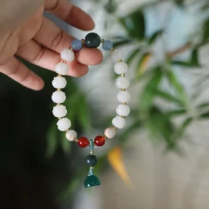 Bodhi seed lotus carved bracelet with white lotus beads and gemstone charms on natural bamboo leaf background