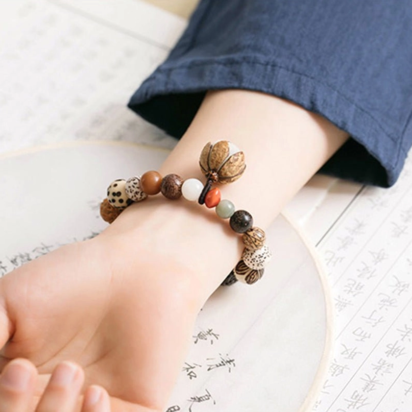 Close-up bodhi seed lotus bracelet on wrist with antique book background detail shot