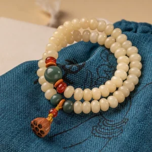 Bodhi seed double wrap bracelet with lotus pod charm, flat lay on embroidered blue cloth with accent beads