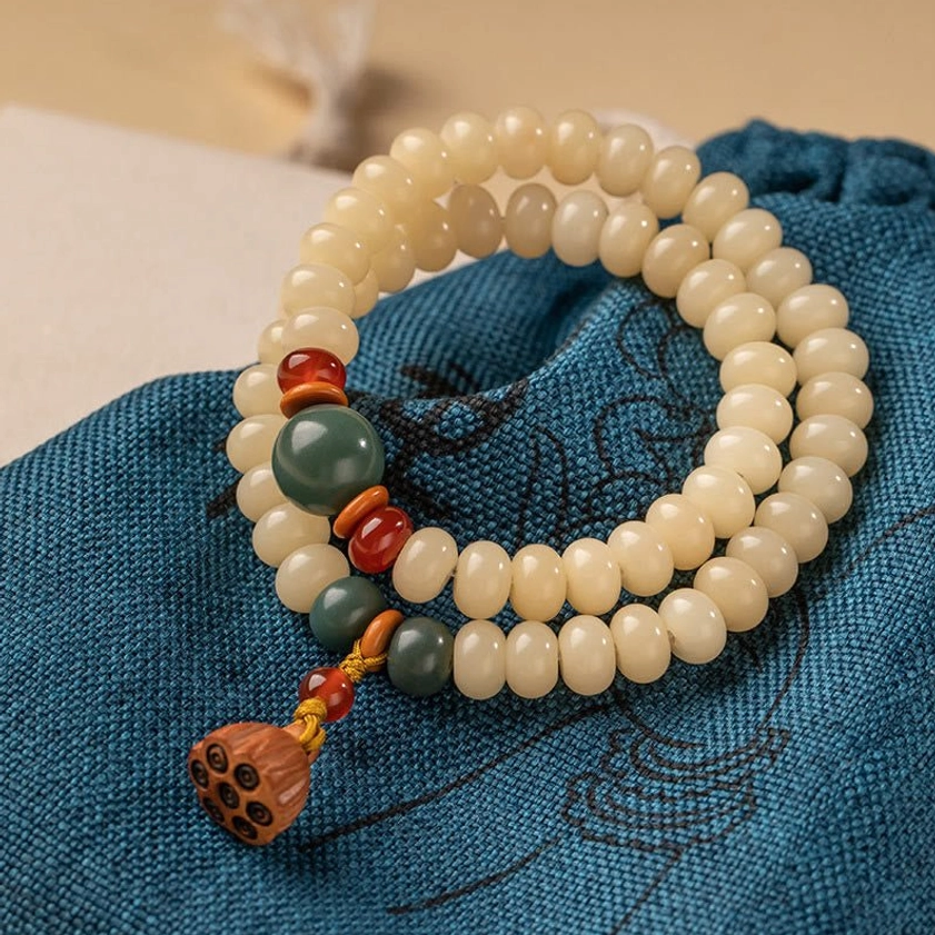 Bodhi seed double wrap bracelet with lotus pod charm, flat lay on embroidered blue cloth with accent beads