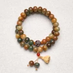 Bodhi seed lotus pod double wrap bracelet flat lay with warm earthy tone beads and wooden charm on grey backdrop