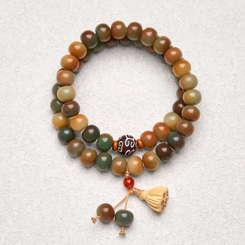 Bodhi seed lotus pod double wrap bracelet flat lay with warm earthy tone beads and wooden charm on grey backdrop