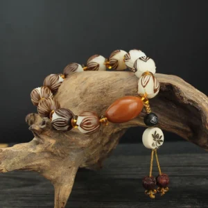 Bodhi seed lotus meditation bracelet with carved lotus beads and brown accent bead displayed on natural driftwood