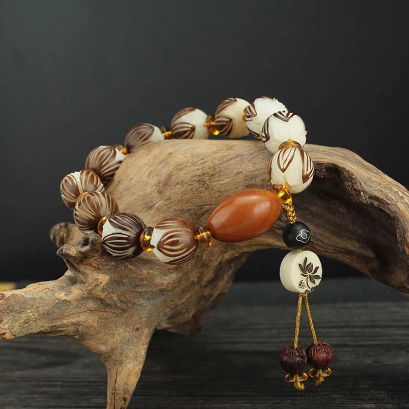 Bodhi seed lotus meditation bracelet with carved lotus beads and brown accent bead displayed on natural driftwood