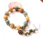 Bodhi seed lotus bracelet with multicolor carved beads and jujube lotus charm on white background, flat lay overhead view
