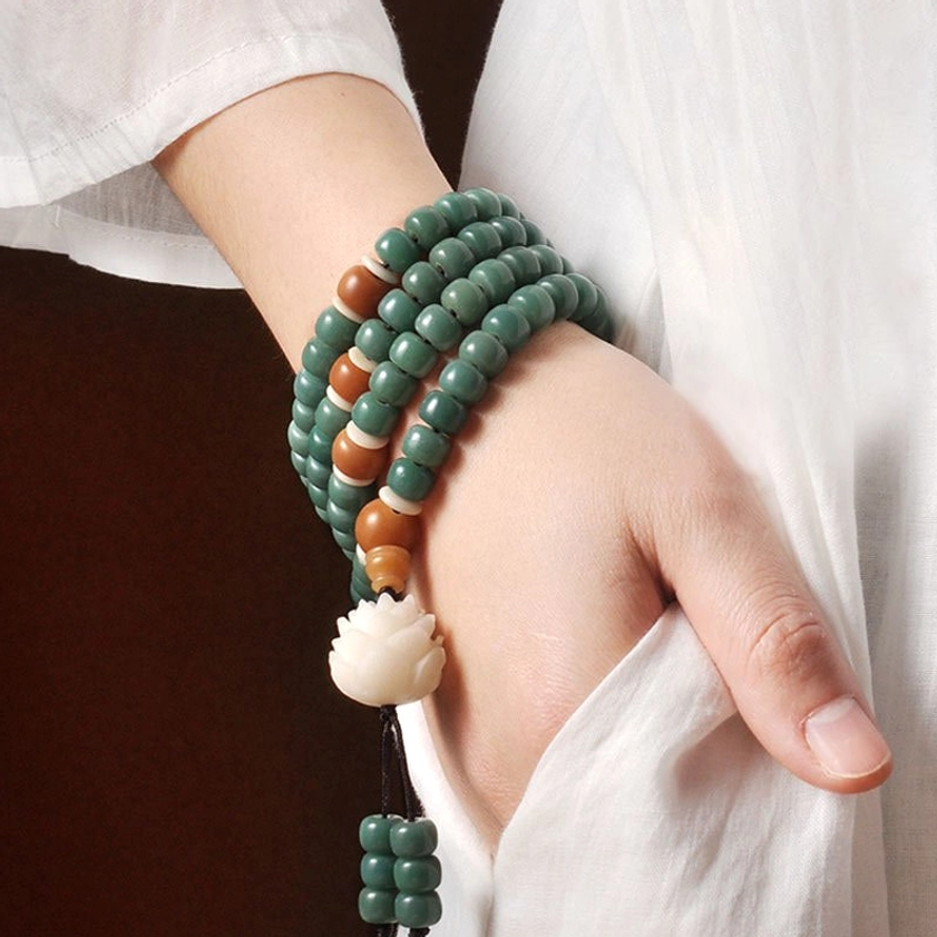 Bodhi seed bracelet worn as multi-layer wrist jewelry on white linen fabric background
