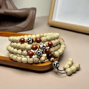 108 Bodhi seed mala beads overhead view showing spotted beige beads with red accent beads and hand-painted Dzi bead pendant on wooden display tray