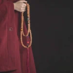 108 Bodhi seed mala beads necklace with hand-painted Dzi bead and red tassel, side view held in hands