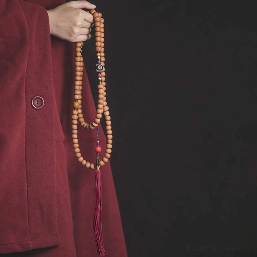 108 Bodhi seed mala beads necklace with hand-painted Dzi bead and red tassel, side view held in hands