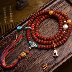 108 bodhi seed Buddhist prayer mala with multicolor tassel on vintage wooden surface, showing detailed carved seed beads and bone accessories