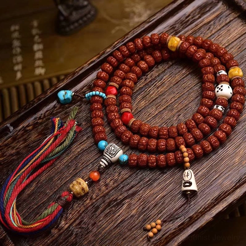 108 bodhi seed Buddhist prayer mala with multicolor tassel on vintage wooden surface, showing detailed carved seed beads and bone accessories