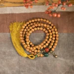 108 bodhi seed mala beads bracelet flat lay with yellow tassel and jade cinnabar accents
