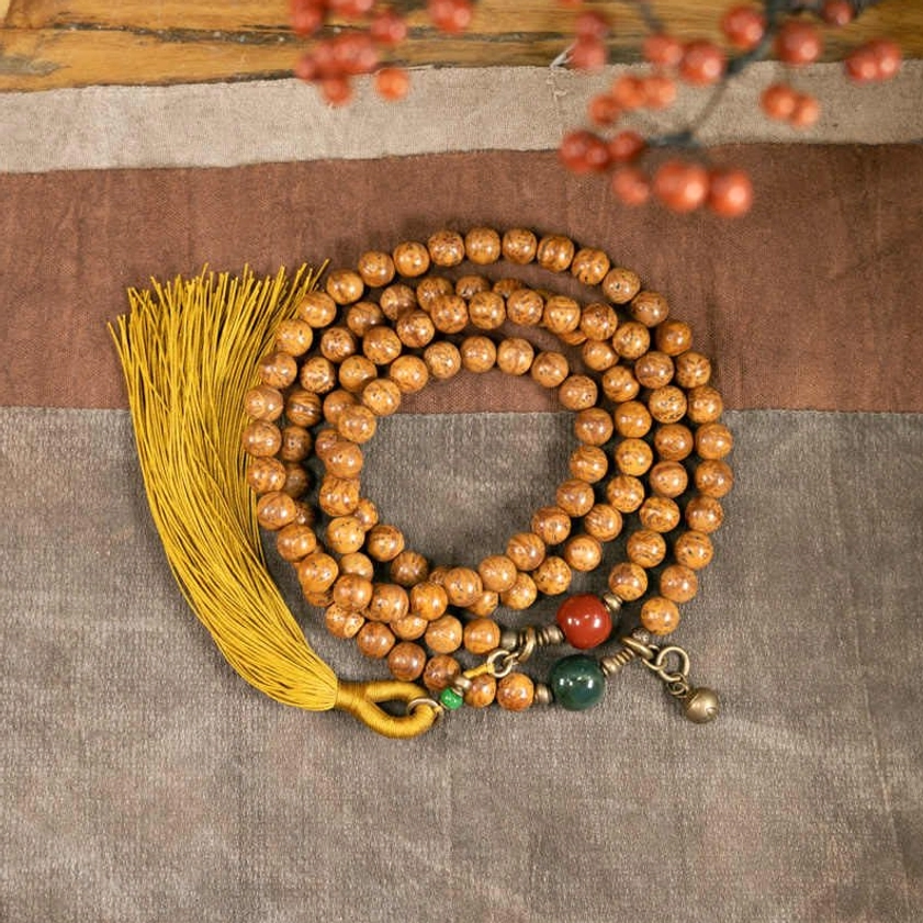 108 bodhi seed mala beads bracelet flat lay with yellow tassel and jade cinnabar accents