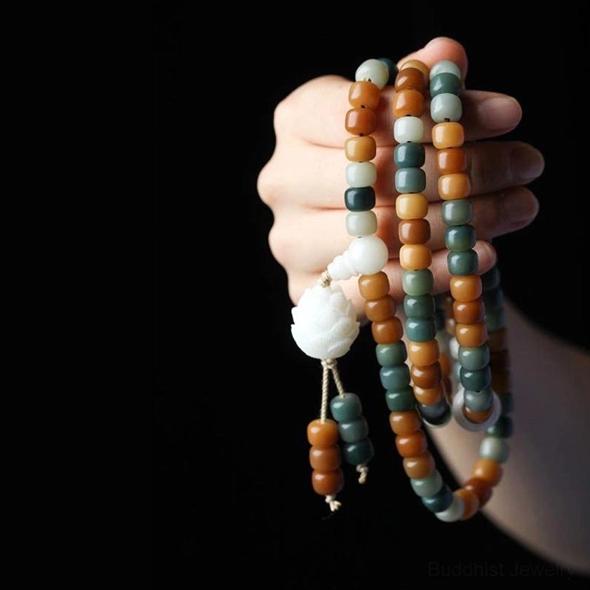 Close-up hand-held bodhi seed prayer beads mala with white lotus charm and silk tassel
