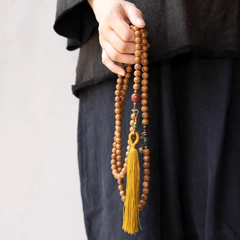 Bodhi seed mala prayer beads bracelet in hand with decorative accessories and yellow tassel