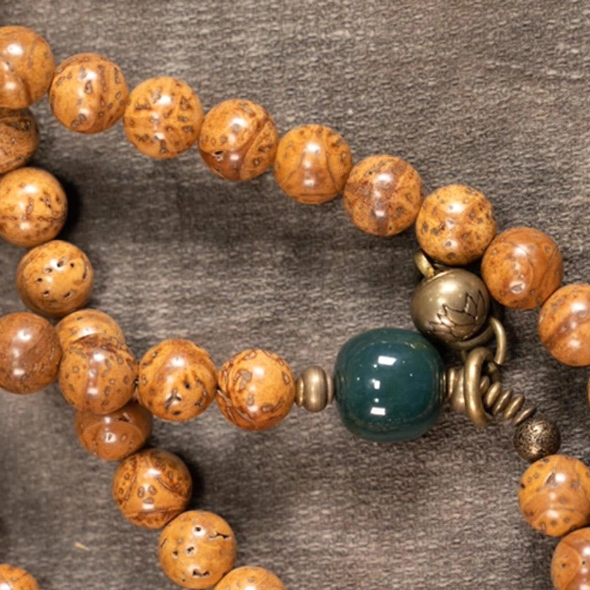 Close-up detail of bodhi seed mala showing natural speckled bead texture and green jade accent