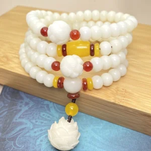 Bodhi seed 108 bead mala bracelet with lotus pendant, flat lay top view on wooden board with blue fabric