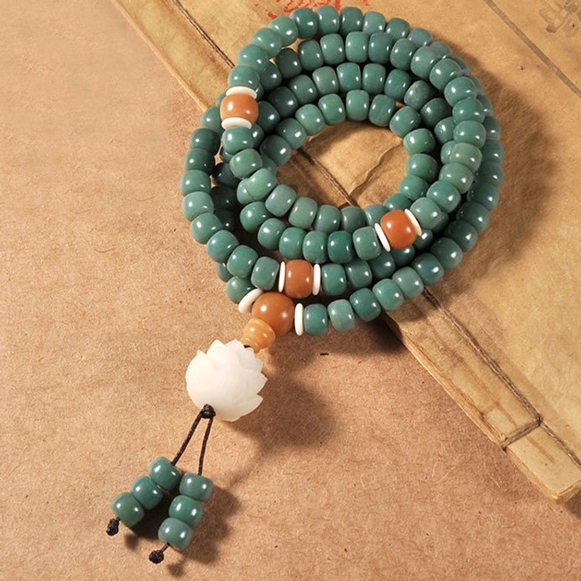 Green bodhi seed prayer beads circular loop with lotus charm and decorative tassel on kraft paper