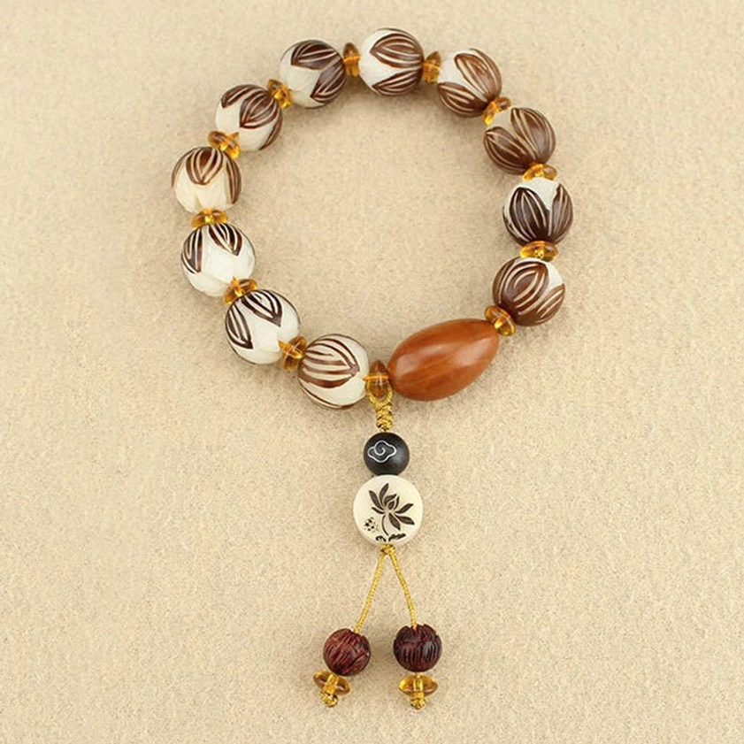 Top-down flat lay of bodhi seed mala bracelet with dual tassel pendant and gold spacer beads on light background