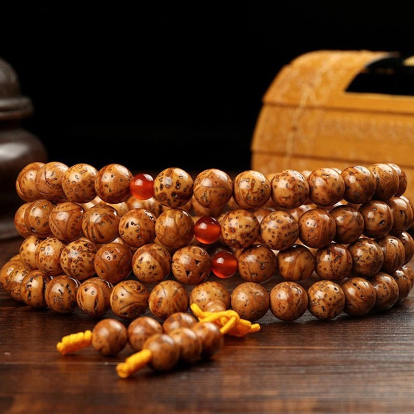 Bodhi seed prayer beads mala side view with wooden storage box showing brown spotted beads yellow tassel and red agate accents