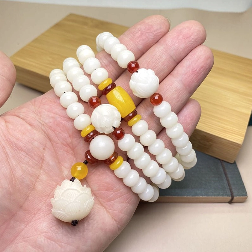 Authentic bodhi seed mala bracelet worn on hand, showing 108 beads and carved lotus bead close up
