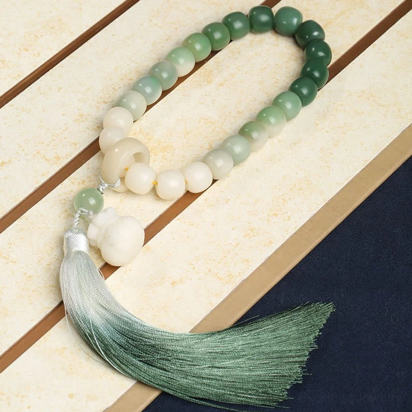 Gradient bodhi seed prayer mala bracelet featuring ombre beads, fortune money bag charm, and long silk tassel on wooden surface - authentic handmade Buddhist meditation bracelet