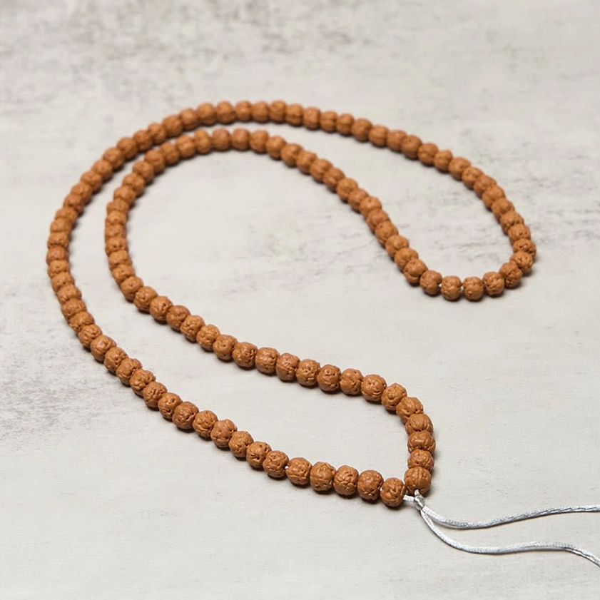 Stretched Buddhist 108 Bodhi seed mala beads full length strand showing slim brown seeds with silver hanging tassel