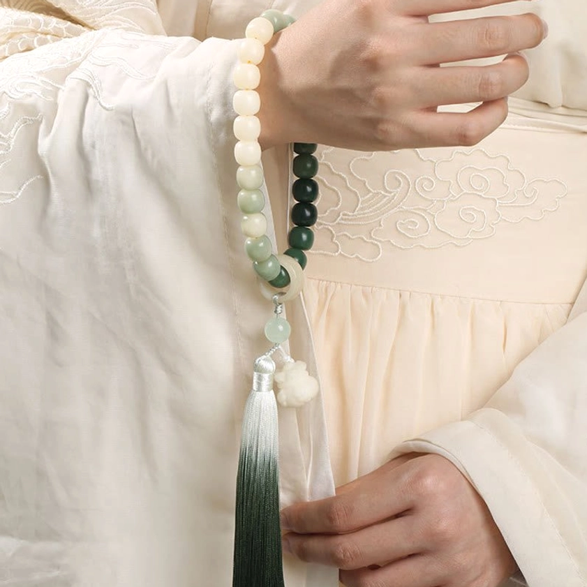 Woman wearing bodhi seed wrist mala with ombre gradient beads and lotus charm on wrist - side view close-up shot showing Buddhist prayer bracelet in traditional setting