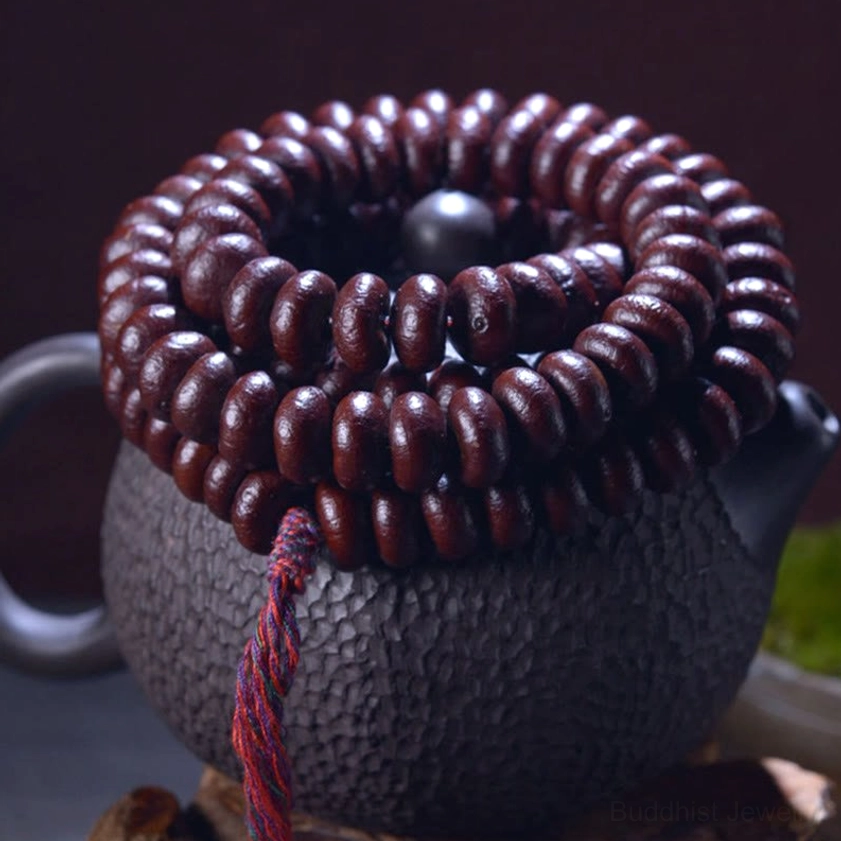 Purple Bodhi Seed 108 mala beads close-up on dark teapot with guru bead and red braided tassel