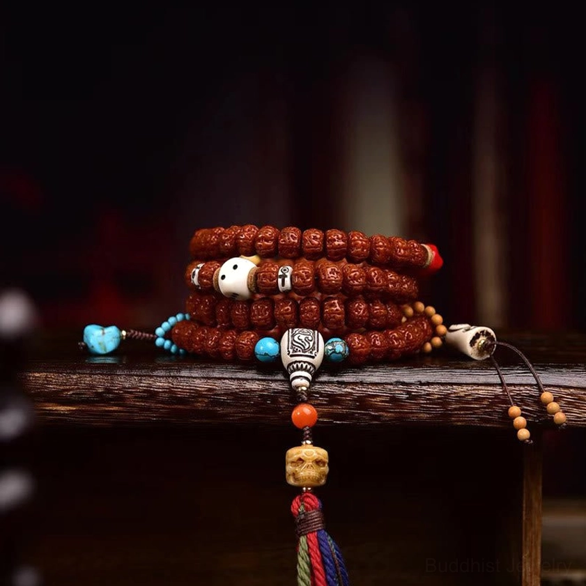 Three-quarter view of 108 bodhi seed Buddhist mala with blue decorative beads and small side tassel on wooden shelf