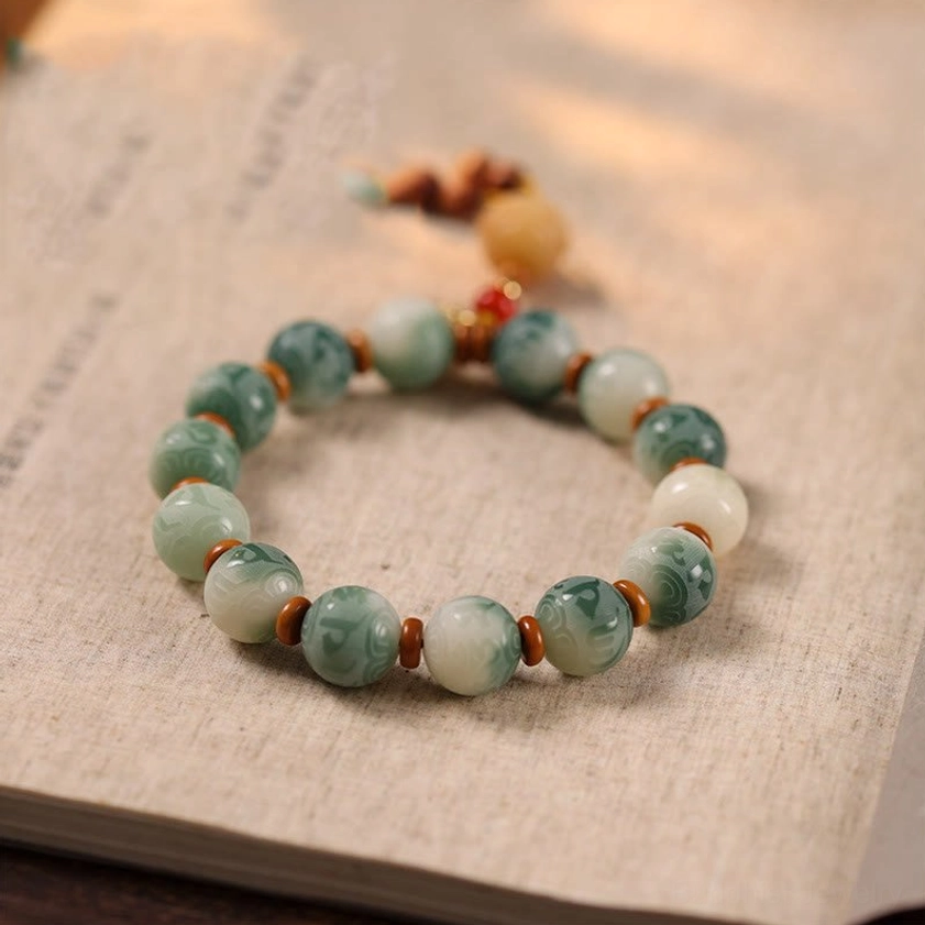 Authentic Bodhi bead bracelet with carved lotus pendant and red tassel on vintage paper surface
