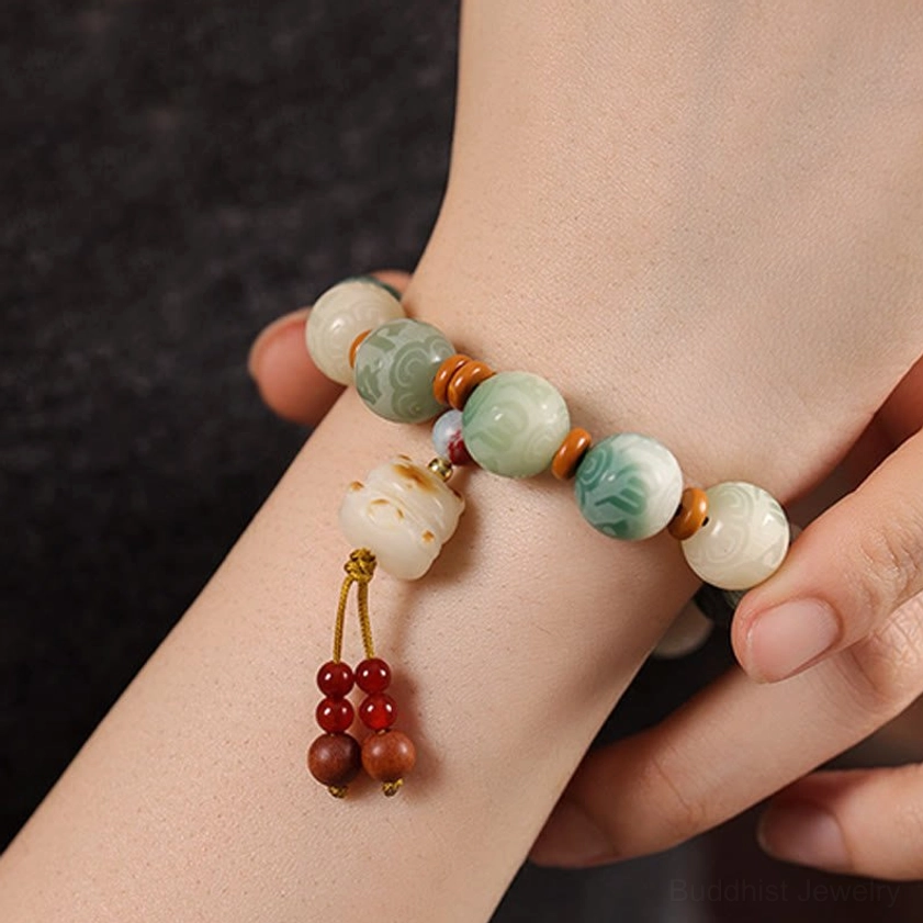 Close-up view of Buddhist Bodhi bracelet worn on wrist with tassel pendant and protective charm