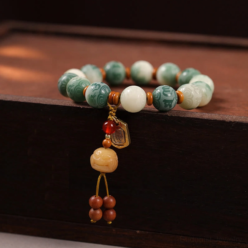 Bodhi seed Om Mani Padme Hum carved bracelet with protective charm pendant displayed on dark wooden surface