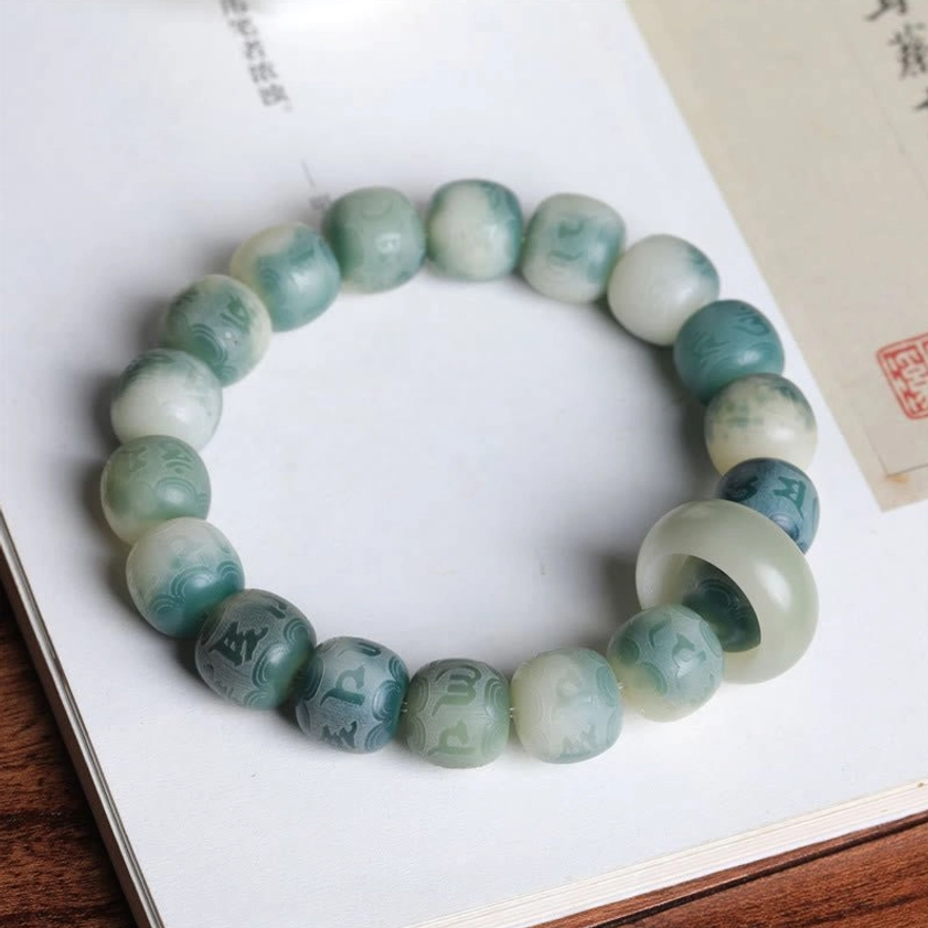 Vintage-style Bodhi seed bracelet with Om Mani Padme Hum engravings displayed on wooden desk and book