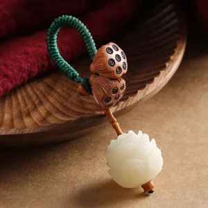 White bodhi seed peach wood lotus keychain with braided green rope and carved lotus pendant on wooden tray