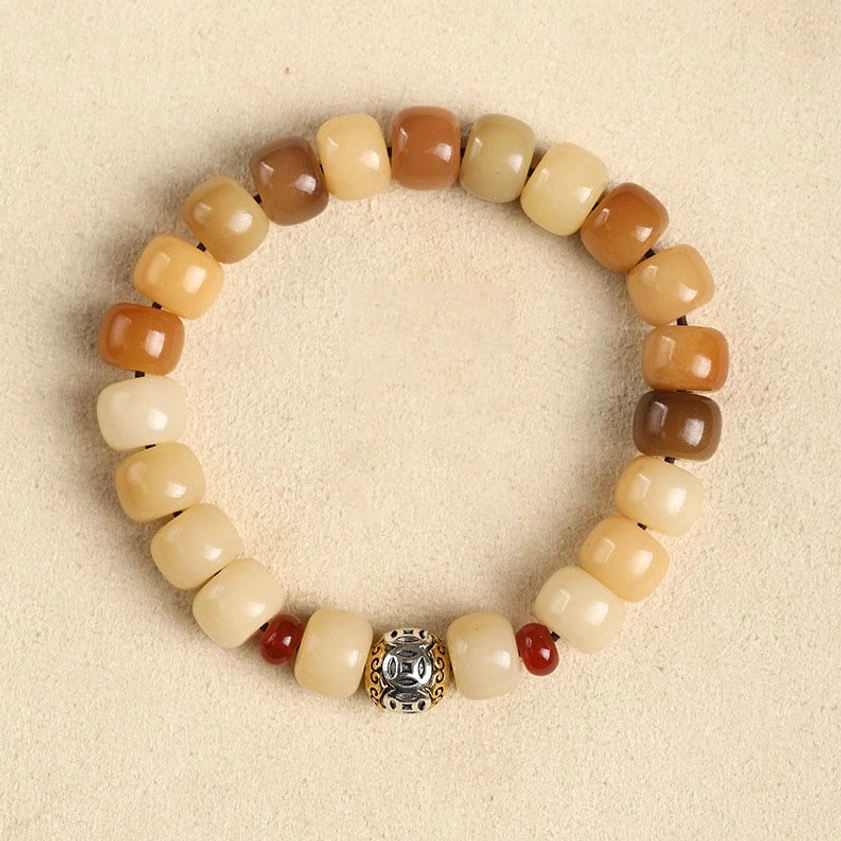 Bodhi seed prayer bracelet overhead flat lay on neutral light studio background with gradient earthy barrel beads and branded silver bead with red accent beads