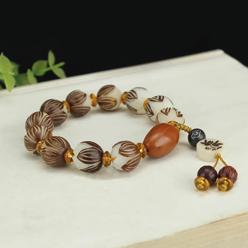 Three-quarter flat lay of bodhi seed prayer bracelet with double wooden tassel pendant and brown focal bead on wooden table