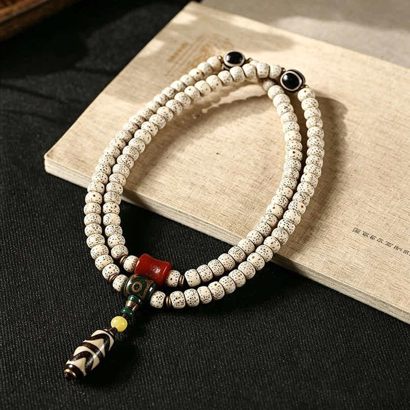 Buddhist prayer bracelet with hand-painted Dzi bead tassel and matte Star Moon Bodhi Seeds displayed on wooden surface