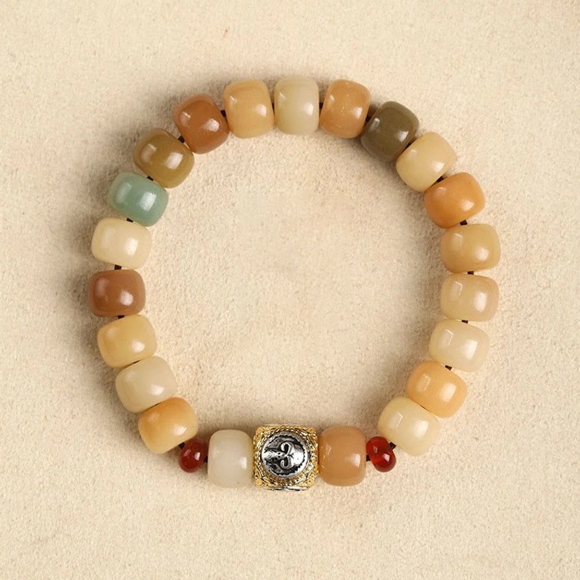 Bodhi seed prayer bracelet overhead flat lay view with gradient earthy beads, silver carved focal bead with red spacers, neutral beige studio background