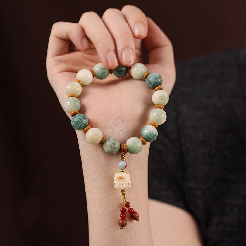 Person wearing Bodhi seed meditation bracelet on hand showing carved beads and tassel pendant detail