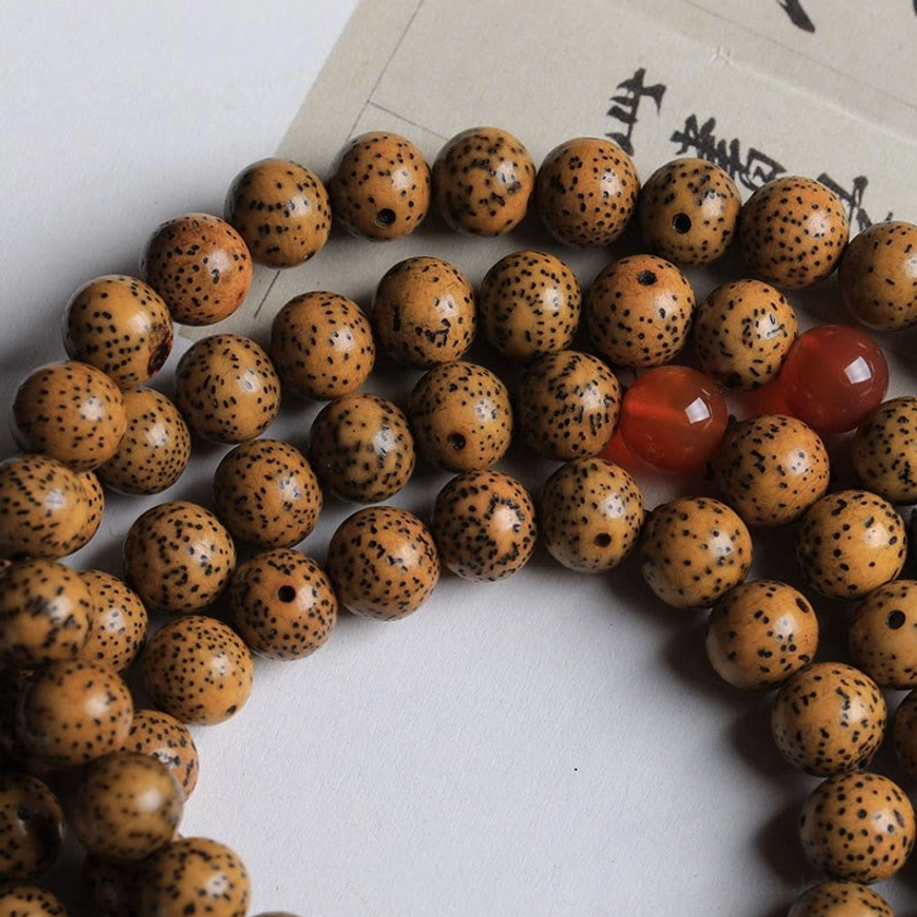 Partial bodhi seed prayer mala overhead close-up view showing brown spotted beads, red agate accents, and natural seed texture of Buddhist 108 mala bracelet